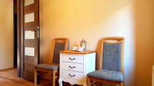 a bedroom with two chairs and a dresser and a door at Apartament Lawenda in Łeba +14 photos