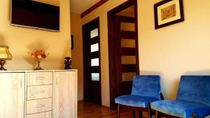 two blue chairs in a living room with a tv at Apartament Lawenda in Łeba