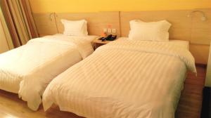 two beds in a hotel room with white sheets at 7Days Inn Langzhong Seven Mile Avenue in Langzhong
