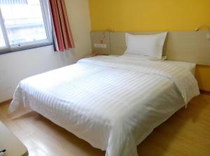 a large white bed in a room with a window at 7Days Inn Yanan East Street Bus Station in Yan'an
