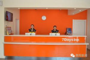Quyang的住宿－7天酒店·保定曲阳太行路汽车站店，两个人坐在橘色墙上的柜台上