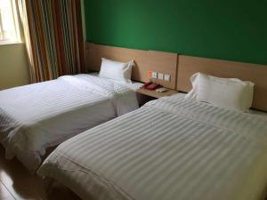 duas camas num quarto de hotel com uma parede verde em 7Days Inn Jintan passenger terminal em Changzhou