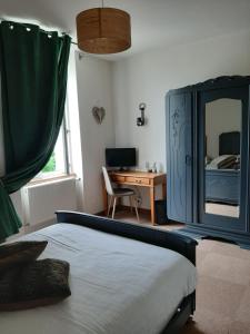 a bedroom with a bed and a desk and a mirror at L'Auberge du Tire Bouchon in Couffé