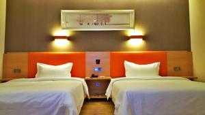 Habitación de hotel con 2 camas y pared de color naranja en 7Days Premium Chongqing Fuling Riverside Avenue, en Fuling