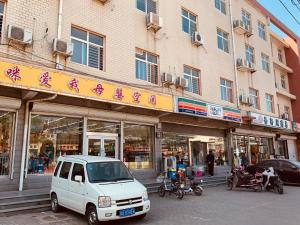 biały van zaparkowany przed budynkiem w obiekcie 7Days Inn 261 Shijiazhuang Zhonghua Street New Railway Station w mieście Shijiazhuang