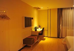 um quarto de hotel com uma secretária e uma televisão na parede em 7Days Premium Shizuishan Dawukou em Shizuishan