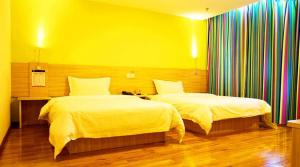 sypialnia z 2 łóżkami i żółtą ścianą w obiekcie 7Days Inn Chongqing Yunyang passenger terminal station w mieście Shuangjiang