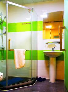 uma casa de banho verde e branca com um lavatório e um chuveiro em 7Days Inn Chongqing Yunyang passenger terminal station em Shuangjiang