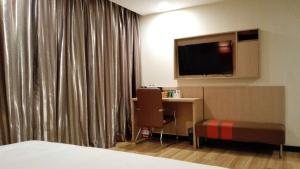 um quarto de hotel com uma cama, uma secretária e uma televisão em 7Days Premium Tangshan Xinhua Road University of science and engineering em Tangshan