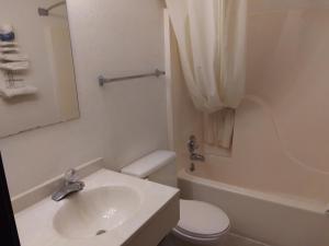 a bathroom with a sink and a toilet and a tub at Amerihost Inn & Suites in Kingdom City