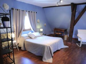 a blue bedroom with a bed and a window at La Maison Bleue in Kientzheim
