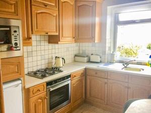 a kitchen with wooden cabinets and a stove top oven at Croft Cottage in Pateley Bridge