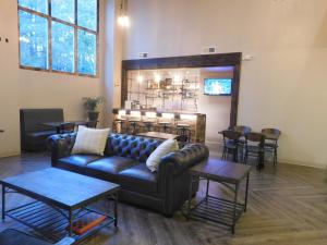 a living room with a leather couch and tables at GreenTree Inn & Suites Pinetop in Pinetop-Lakeside