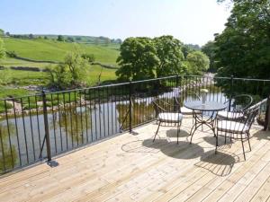 a patio with a table and chairs on a wooden deck at Rose Cottage in Grassington