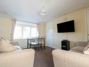 a living room with two chairs and a flat screen tv at Brewery Lodge in Lydney