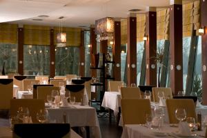 a restaurant with white tables and chairs and windows at Holiday Beach Budapest Wellness Hotel with Sauna Park in Budapest