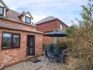a brick house with a table and an umbrella at Beacon Cottage in Great Malvern +7 photos