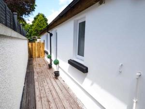 テンビーにあるWhite Cottage Annexeの白い建物で、窓のある木製デッキが付いています。