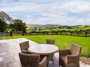 une terrasse avec une table, des chaises et un champ dans l'établissement Beudy, à Llangwm 3 autres photos