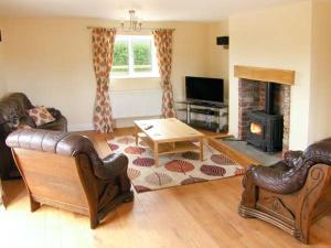 a living room with leather furniture and a fireplace at Hendre in Denbigh