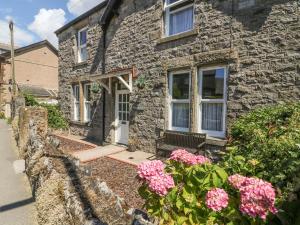 a stone house with pink flowers in front of it at Riverside View in Grange Over Sands