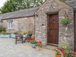 a stone building with a wooden door and flowers at Rosegarth Cottage in Morland
