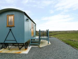 a blue tiny house with a bench on the front at Llety'r Bugail in Holyhead