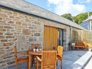 a patio with a wooden table and chairs at The Stable, Boskensoe Barns in Falmouth