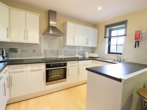 a kitchen with white cabinets and a black counter top at Savita Cottage in Girvan