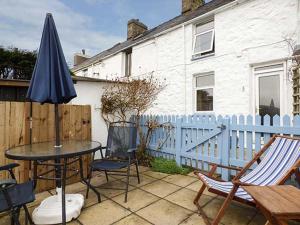 a patio with a table and chairs and an umbrella at Merlin in Pwllheli