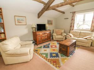 uma sala de estar com mobiliário branco e uma televisão em The Granary em Kirkby Lonsdale