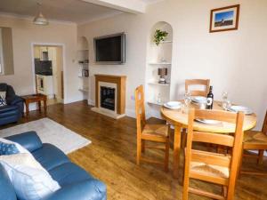 a living room with a table and a dining room at Ty Twt in Burry Port