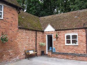 a brick building with a bench in front of it at Finwood Cottage 1 in Rowington