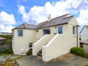 a white house with a staircase in front of it at Ty'r Enfys Bach - Upper in Trearddur