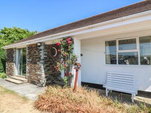 uma casa com um banco à frente em The Shack em Mawgan Porth