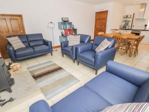 a living room with blue couches and a table at Middlefell View Cottage in Alston