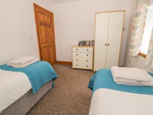 a small bedroom with two beds and a dresser at Wellhope View Cottage in Alston