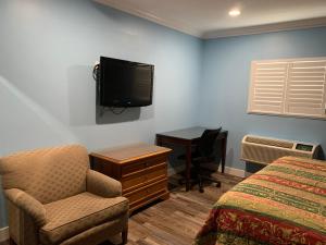 a bedroom with a bed and a chair and a tv at Redondo Beach Motel - LAX in Gardena
