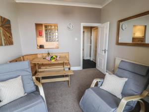 a living room with two blue chairs and a table at Seaview Apartment in Barmouth