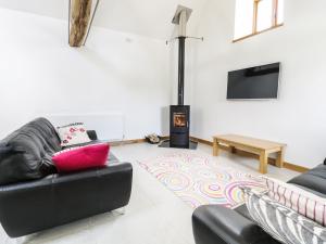 a living room with a black leather couch and a fireplace at Tyddyn Isa in Denbigh