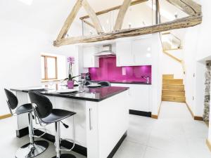 a kitchen with white cabinets and purple walls at Tyddyn Isa in Denbigh