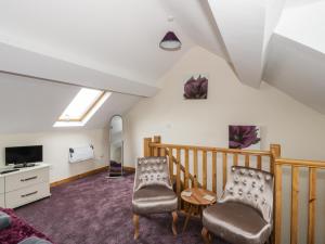 uma sala de estar com duas cadeiras e uma televisão em Butchers Arms Cottage em Llong