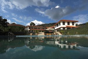 a swimming pool in front of a house and a building at Amritara Ambatty Greens Resort in Virajpet