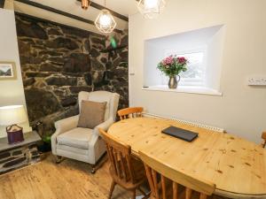 uma sala de jantar com uma mesa de madeira e uma parede de pedra em Ty Coed em Llanberis