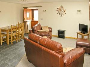 a living room with a leather couch and a table at Ty Isaf Penrhyddion in Betws-y-coed