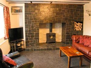 a living room with a fireplace with a couch and a tv at Hendre Aled Farmhouse in Llansannan