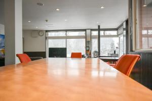 una gran sala de conferencias con una mesa grande y sillas naranjas en Asuka Lodge, en Hakuba