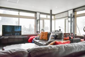 a living room with a couch and a tv at Asuka Lodge in Hakuba