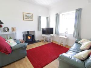a living room with a couch and a red rug at Trigfa Cottage in Abersoch +6 photos