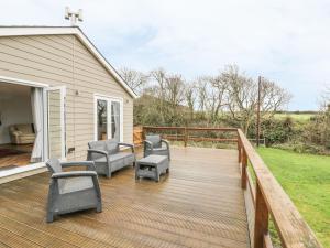 a deck with chairs and tables on a house at Nant Y Felin Lodge in Aberdaron